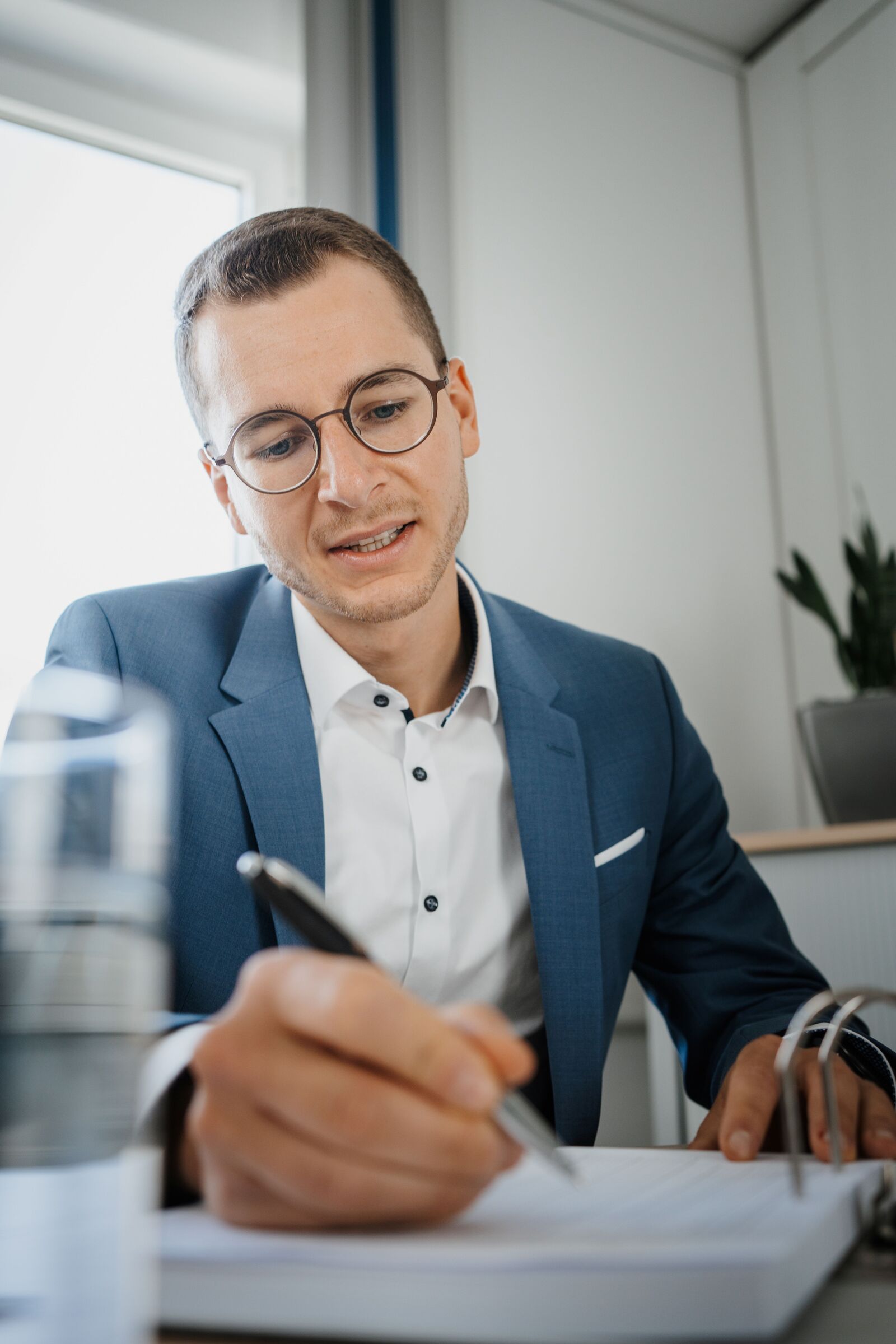 Ein Foto von Geschäftsführer Nick Neumann, der an einem Tisch sitzt, einen Stift in der Hand hält und etwas notiert.